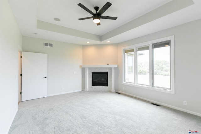 unfurnished living room featuring visible vents, carpet, a tray ceiling, and a fireplace
