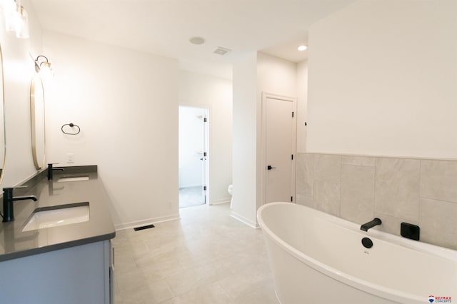bathroom featuring a sink, visible vents, double vanity, and a freestanding bath
