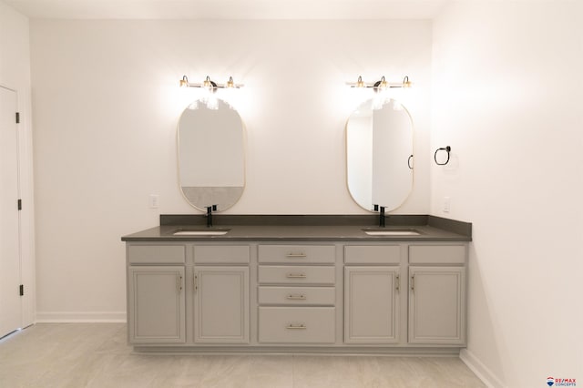 full bath featuring double vanity, a sink, and baseboards