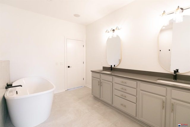 full bath with double vanity, a freestanding tub, and a sink