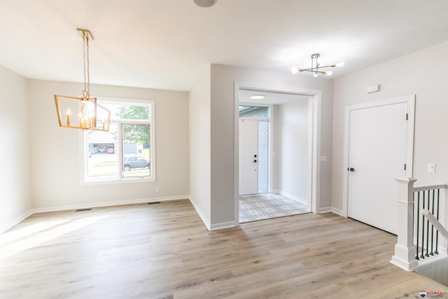 entryway with an inviting chandelier, light wood-style floors, and baseboards