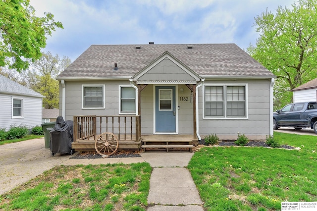 bungalow featuring roof with shingles and a front yard