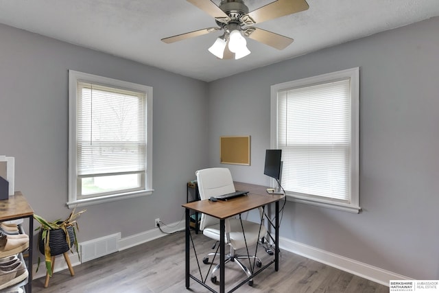 home office with baseboards, visible vents, and wood finished floors