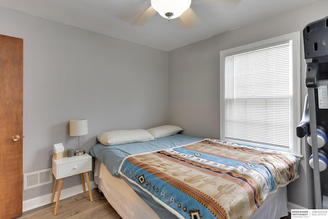 bedroom with baseboards, ceiling fan, visible vents, and wood finished floors