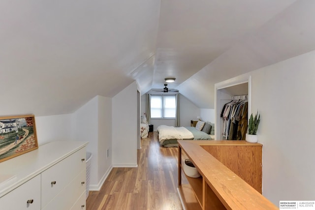 bedroom with light wood-style floors, a ceiling fan, baseboards, and lofted ceiling