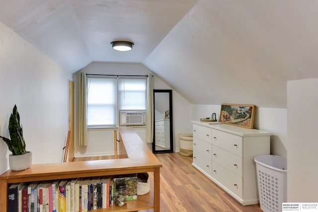 bedroom with cooling unit, light wood-type flooring, and lofted ceiling