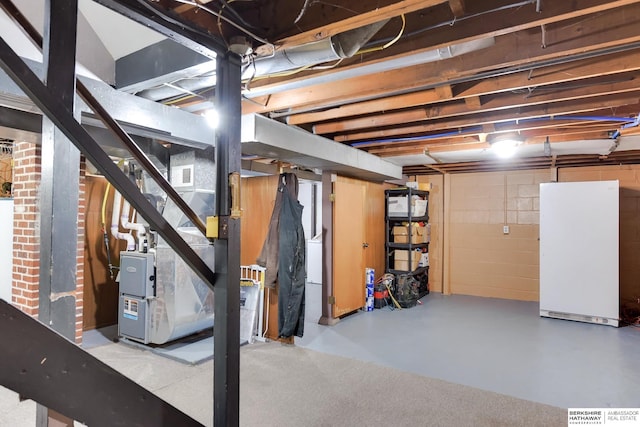 unfinished below grade area featuring freestanding refrigerator and stairs