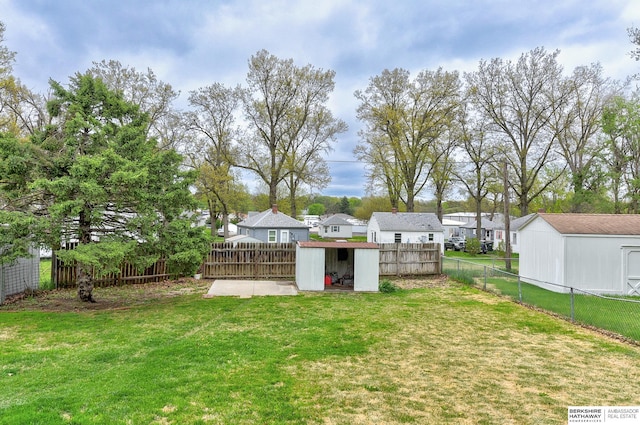 view of yard with an outdoor structure, a residential view, a shed, and a fenced backyard