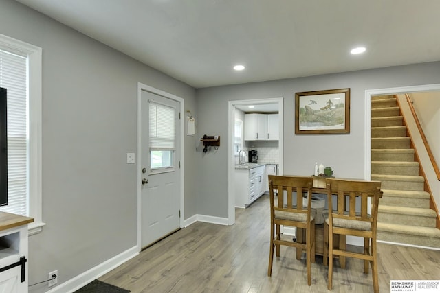 dining room with recessed lighting, light wood-type flooring, and stairs