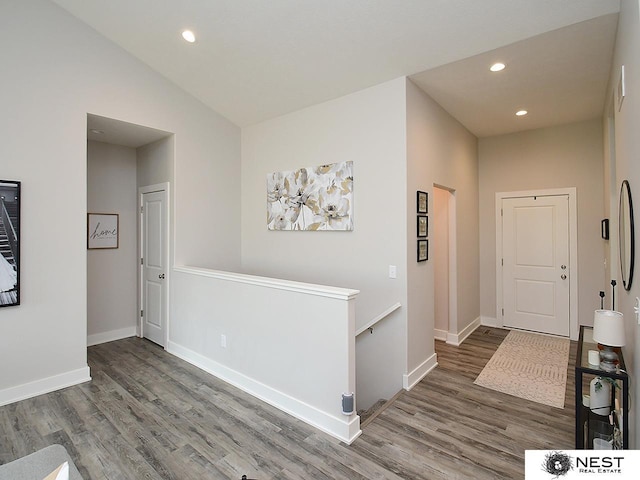 corridor with baseboards, recessed lighting, wood finished floors, and an upstairs landing