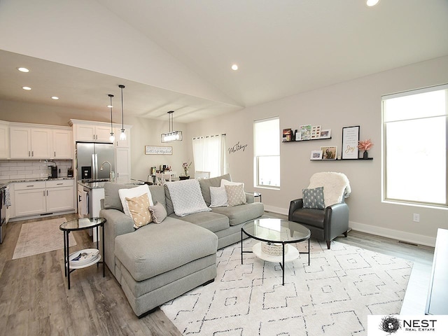 living area featuring recessed lighting, visible vents, vaulted ceiling, and light wood-style floors