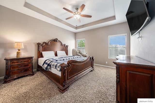 bedroom with baseboards, light carpet, ceiling fan, and a raised ceiling