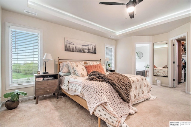 bedroom featuring carpet flooring, a tray ceiling, visible vents, and baseboards