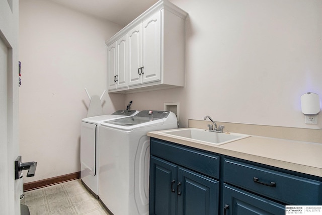 washroom with cabinet space, washing machine and clothes dryer, a sink, baseboards, and light floors