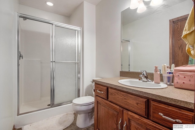 bathroom featuring vanity, a shower stall, and toilet