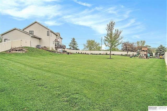 view of yard with fence, central AC unit, and a playground