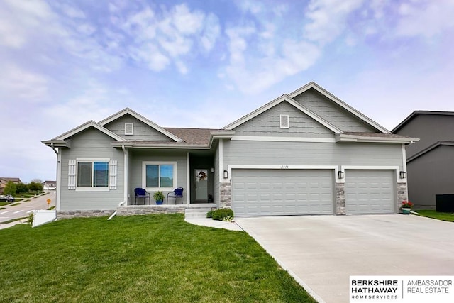 craftsman house with stone siding, driveway, a front yard, and a garage