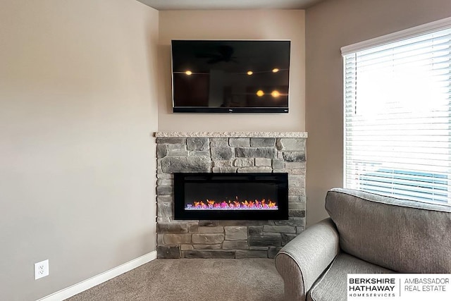 room details with ceiling fan, carpet floors, baseboards, and a stone fireplace