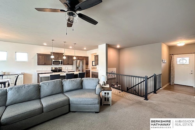 living area with a ceiling fan, recessed lighting, and light colored carpet