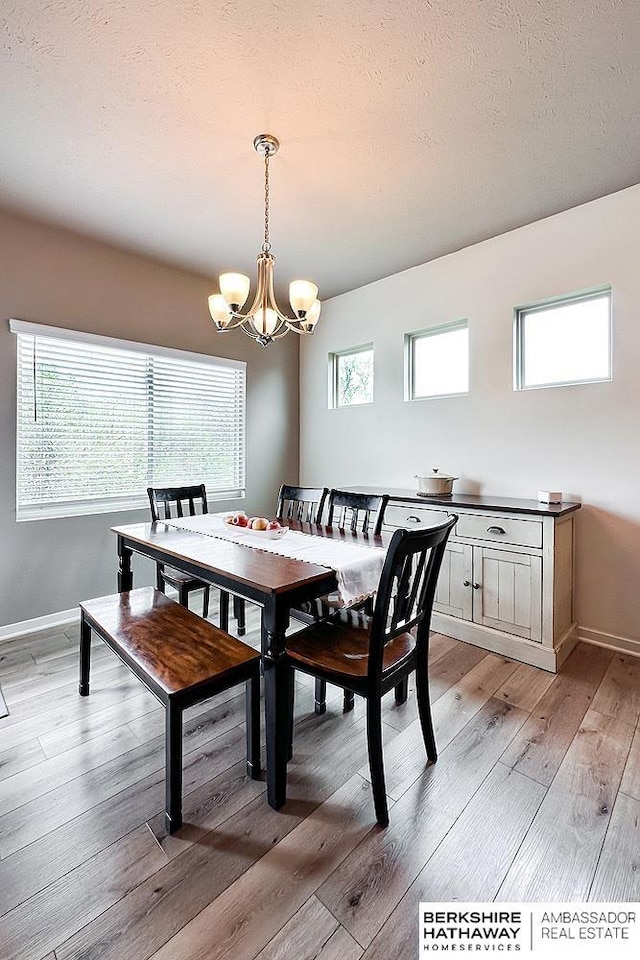 dining space with baseboards, a chandelier, a wealth of natural light, and light wood-style flooring