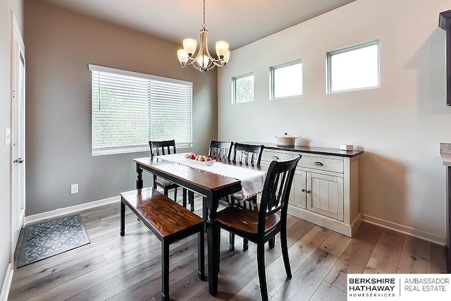 dining room featuring baseboards, light wood-style flooring, and a chandelier