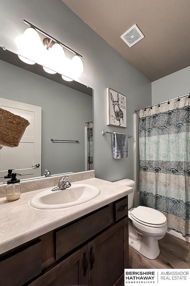 bathroom featuring visible vents, vanity, wood finished floors, toilet, and a shower with shower curtain