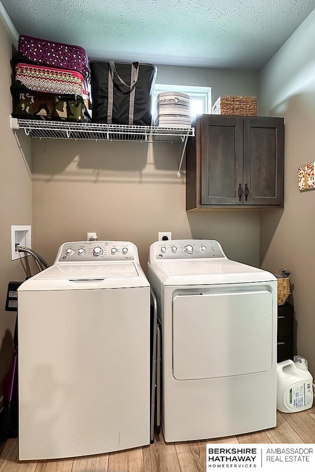 washroom featuring light wood-type flooring, cabinet space, and washing machine and clothes dryer