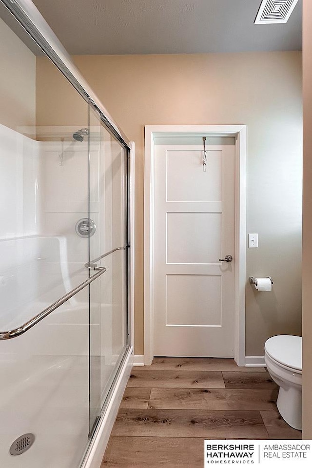 full bath featuring visible vents, a shower stall, wood finished floors, baseboards, and toilet
