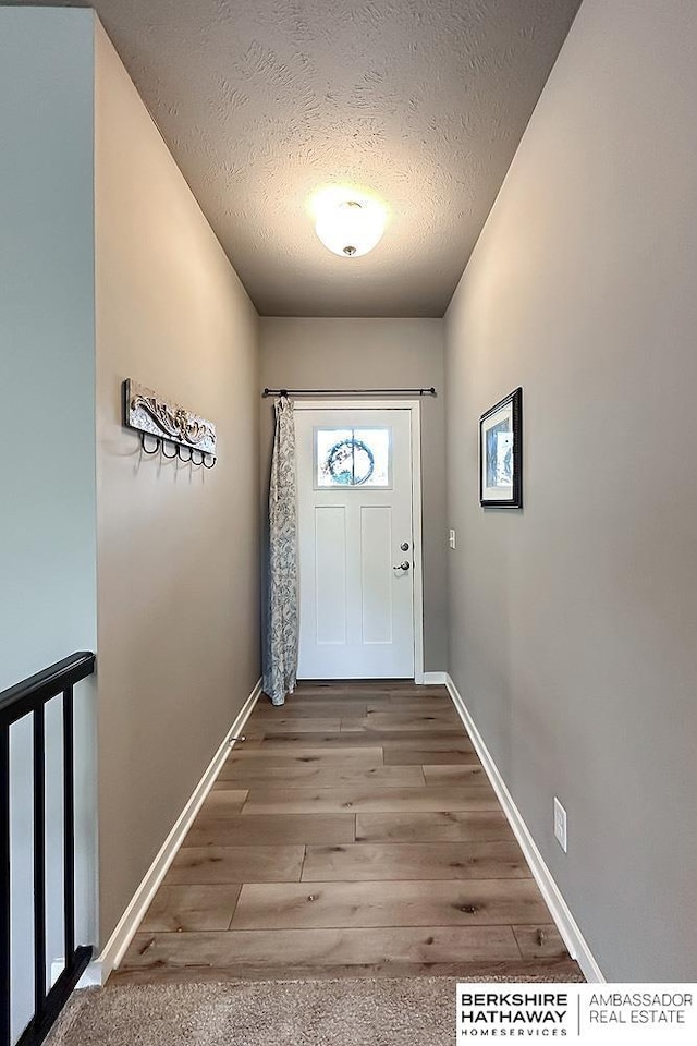 entryway with baseboards, a textured ceiling, and wood finished floors
