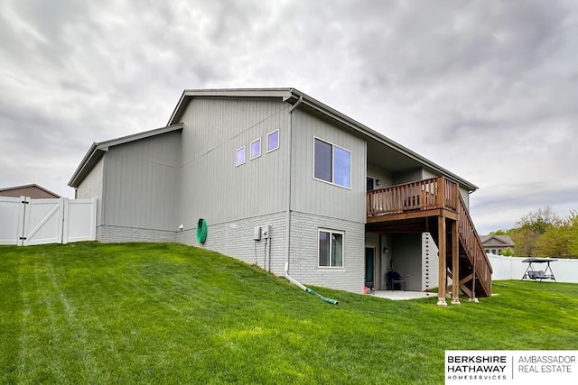 rear view of house with a lawn, a gate, a deck, and fence
