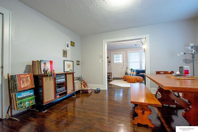 dining room with a textured ceiling, baseboards, and wood finished floors