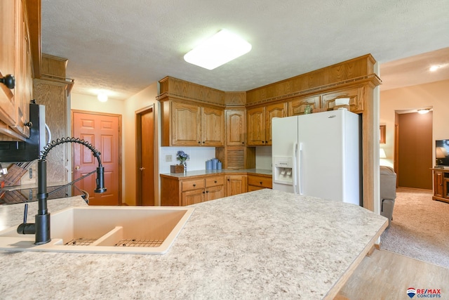kitchen with a sink, light countertops, white fridge with ice dispenser, and light wood-type flooring