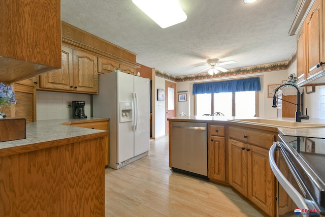 kitchen with a textured ceiling, a peninsula, dishwasher, and white refrigerator with ice dispenser