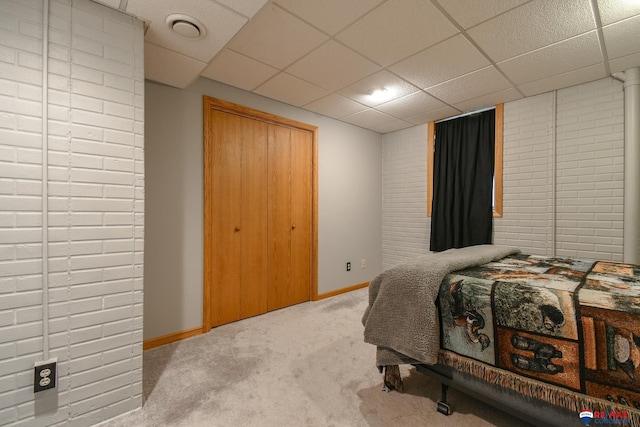 carpeted bedroom with baseboards, a drop ceiling, and a closet