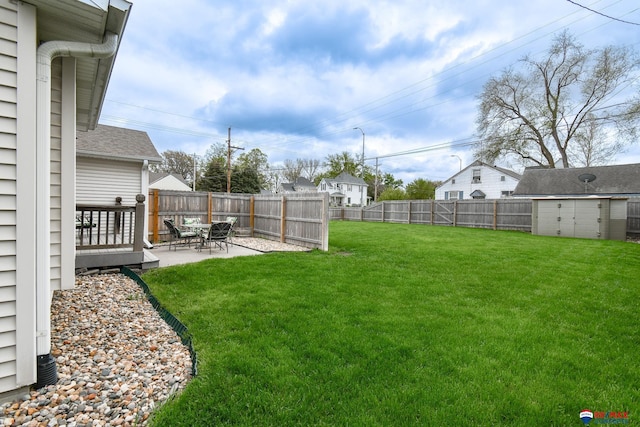 view of yard featuring a patio, a fenced backyard, a storage unit, and an outdoor structure