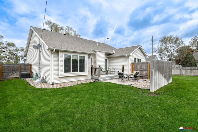 rear view of house with a patio, a shingled roof, a lawn, and a fenced backyard