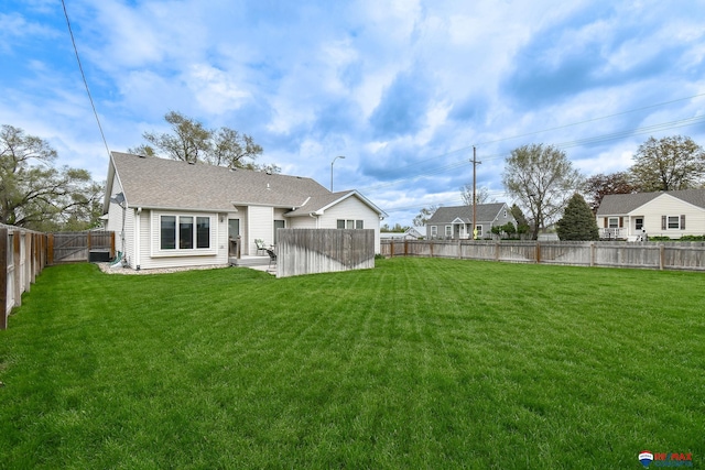 rear view of property with a lawn, a fenced backyard, and roof with shingles