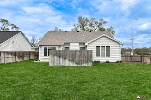 rear view of house featuring a fenced backyard, a yard, and roof with shingles