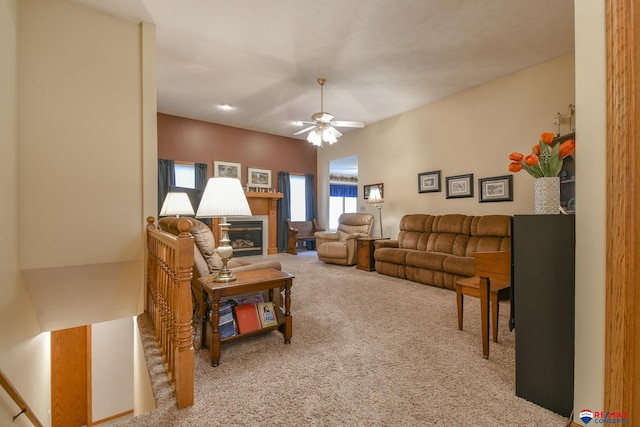 living room featuring a ceiling fan, a glass covered fireplace, and carpet