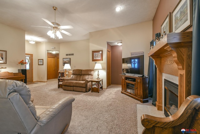 living area with ceiling fan, light colored carpet, visible vents, a tile fireplace, and baseboards