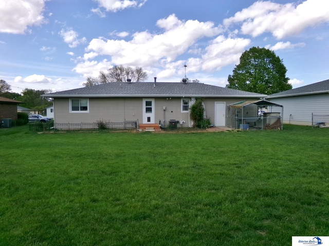 rear view of house featuring entry steps, central air condition unit, a shingled roof, and a yard