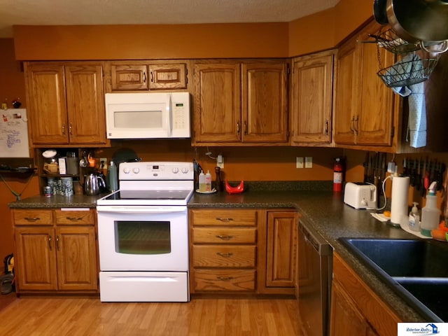 kitchen with brown cabinetry, white appliances, and light wood-type flooring