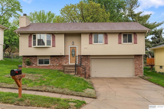 bi-level home with brick siding, a garage, a front yard, a chimney, and concrete driveway
