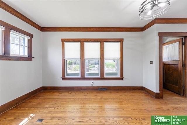 empty room with crown molding, baseboards, and light wood finished floors