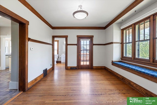 unfurnished room featuring baseboards, ornamental molding, and wood finished floors