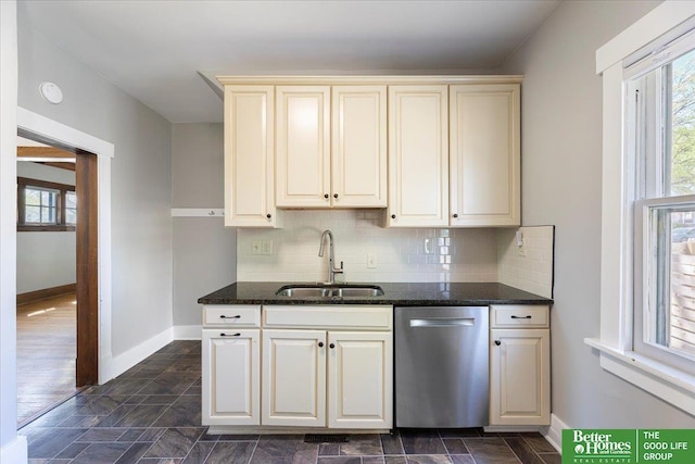 kitchen with baseboards, a sink, dishwasher, and cream cabinets