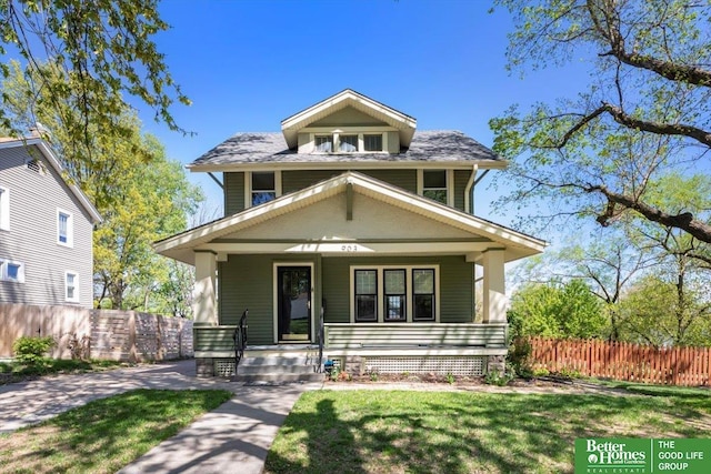 american foursquare style home with a front lawn, fence, and covered porch