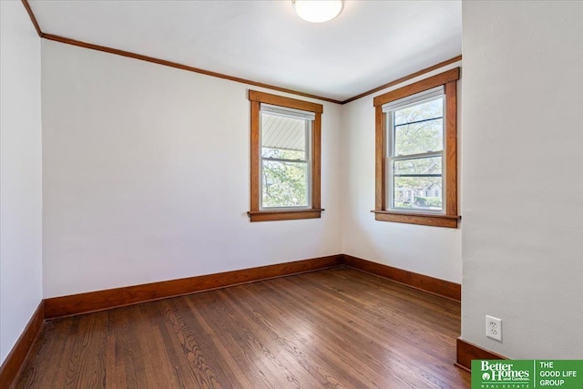 spare room featuring baseboards, ornamental molding, and dark wood-style floors