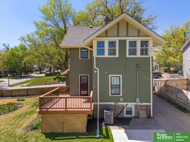 rear view of house with fence, a deck, cooling unit, roof with shingles, and a chimney