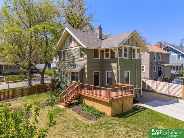 back of property featuring fence, board and batten siding, a deck, concrete driveway, and a yard